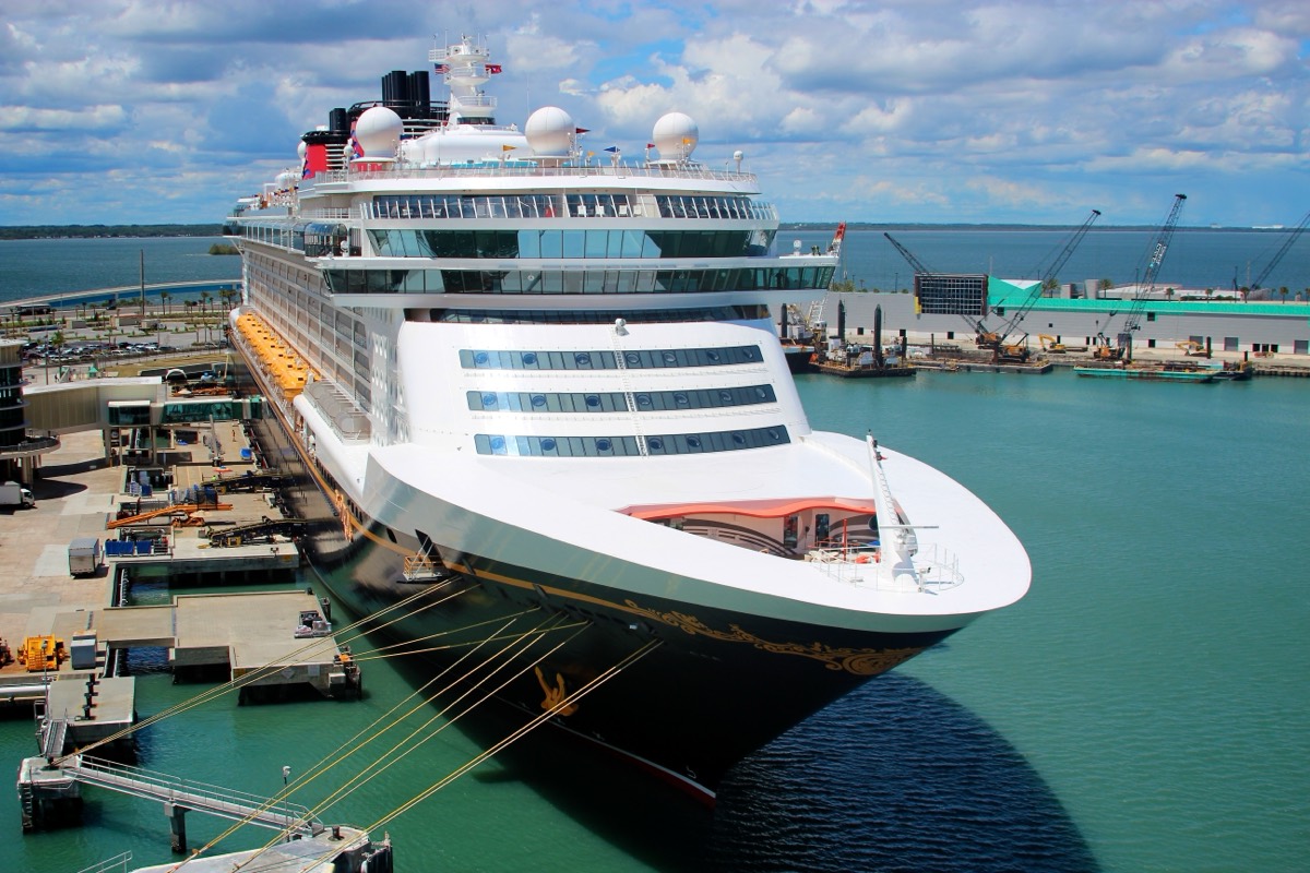 A large cruise ship docked at a terminal at Port Canaveral on a clear morning.