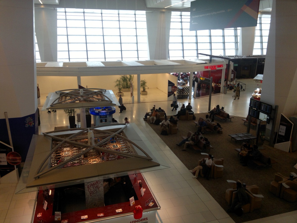 Travelers waiting in line at an immigration counter in an Indian international airport terminal.