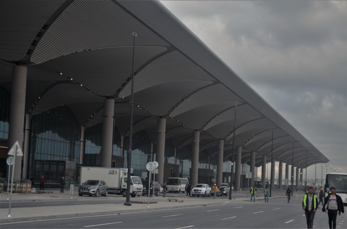 Travelers walking through the bright, high-ceilinged departures hall at Istanbul Airport.